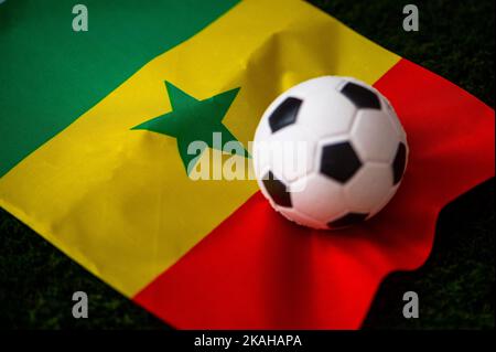 Équipe nationale de football du Sénégal. Drapeau national sur l'herbe verte et le ballon de football. Papier peint pour le championnat et le tournoi de football en 2022. Stagiaire mondial Banque D'Images