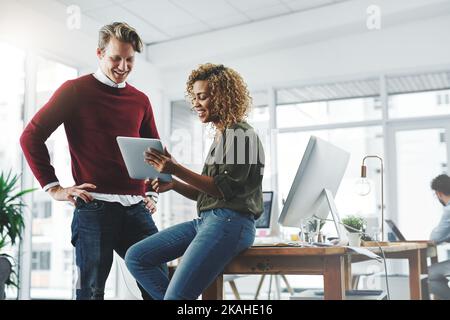 Le travail d'équipe et la technologie font avancer les choses. Deux jeunes collègues utilisent une tablette numérique dans un bureau moderne. Banque D'Images