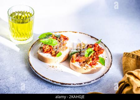 Gros plan d'un verre de limonade aux figues et de deux tranches de pain au fromage feta, aux tomates rôties et au basilic Banque D'Images