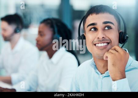 Heureux, le centre d'appel et l'homme en pause pensent à la solution crm ou contactez-nous stratégie avec un regard enthousiaste au bureau. Personne indienne de télémarketing dans Banque D'Images