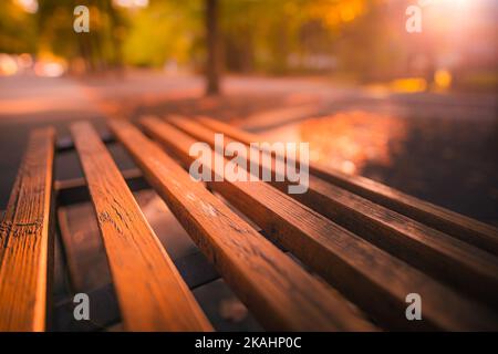 Banc de parc automne paysage urbain automne loisirs. Coucher de soleil paisible et reposant, près d'un banc en bois avec forêt de bokeh brouillée, rayons du soleil. Idyllique Banque D'Images