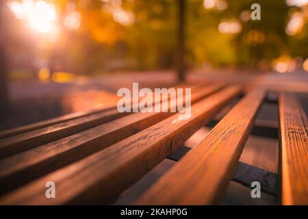 Banc de parc automne paysage urbain automne loisirs. Coucher de soleil paisible et reposant, près d'un banc en bois avec forêt de bokeh brouillée, rayons du soleil. Idyllique Banque D'Images