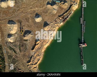 Vue aérienne de la mine minérale et de l'équipement d'extraction par un lac calme en fin d'après-midi, mettant en évidence l'activité industrielle et les paysages. Banque D'Images