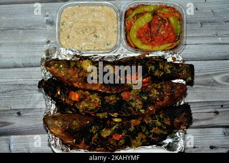 Palets grillés au charbon de bois avec persil et tomate, aubergine marinée et sauce tahini, barbecue et servi dans une assiette jetable sur papier d'aluminium Banque D'Images