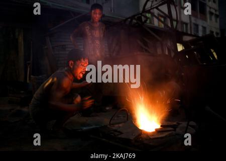 Un employé jette des pigees métalliques dans le four pour les faire fondre. L'industrie de la construction navale au Bangladesh se répand rapidement là où les travailleurs de tous âges travaillent ensemble, à Dhaka, au Bangladesh, sur 28 avril 2016. Les conditions de travail sont graves et ne conviennent pas aux enfants. Les conditions sont chaudes et souvent dangereuses. Même les travailleurs n'utilisent pas de protection minimale. Par conséquent, les accidents se produisent très fréquemment. Les enfants qui travaillent ici grandissent sans éducation, ce qui les a menés vers un avenir incertain. La raison du travail des enfants dans de telles conditions de travail dangereuses est le travail bon marché et la pauvreté Banque D'Images