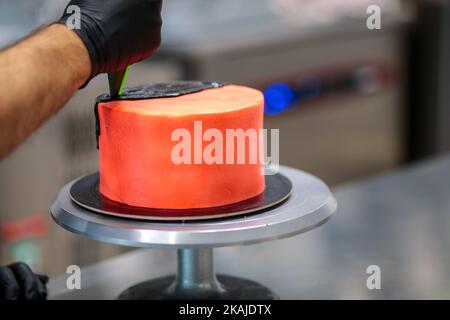 garniture d'un gâteau rouge avec glaçage noir au chocolat noir Banque D'Images