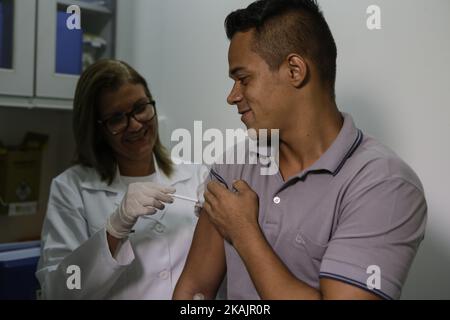 Une infirmière de la FIOCRUZ Foundation applique le vaccin contre la dengue à l'étudiant en administration Denis Paulo da Silva, 22 ans, qui s'est porté volontaire pour le dépistage du vaccin à Recife, dans le nord-est du Brésil. Le 11 novembre 2016, l'Institut Butantan de São Paulo a mis au point le premier vaccin tétravalent brésilien contre la dengue et procède actuellement à des tests sur des volontaires pour garantir la qualité de la lutte contre l'épidémie. Séché par le moustique Aedes aegypti. Selon le ministère brésilien de la Santé, le nombre de cas de dengue a augmenté de 130% en deux semaines et dépasse 200 dossiers par heure dans le pays Banque D'Images