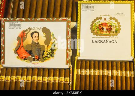 Cigares cubains exposés dans une vitrine. Ces cigares sont roulés à partir de feuilles de tabac trouvées dans tout le pays de Cuba. Le mastic, le liant et l'emballage peuvent provenir de différentes parties de l'île. Toute la production de cigares à Cuba est contrôlée par le gouvernement cubain, et chaque marque peut être enroulée dans plusieurs usines différentes à Cuba. Cuba produit à la fois des cigares faits à la main et des cigares fabriqués à la machine. Toutes les boîtes et étiquettes sont marquées Hecho en Cuba (espagnol pour Made in Cuba). Les cigares à petits pains faits à la machine, finis à la main, ajoutent Hecho un mano, tandis que les cigares entièrement faits à la main disent Totalmente un mano dans le texte de script, cependant Banque D'Images