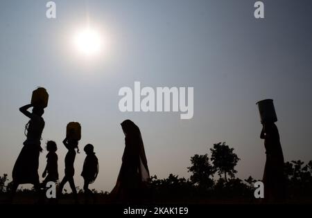 Dans cette photo prise sur 15 décembre,2016,les Indiens d'une communauté autochtone 'Kol' transportent de l'eau potable dans des conteneurs en acier et en plastique, en marchant vers leurs abris temporaires , dans le village de Ralaiora, à environ 80 km d'Allahabad. 'Kol' est l'une des rares communautés autochtones du centre de l'inde. Environ 40 familles avec 200 refuges dans ce village isolé. Les villageois obtiennent leur eau potable d'un puits, à 3 km de leurs abris, car la crise de l'eau potable est le principal et le problème de base dans cette région éloignée. Les hommes gagnent leur vie en travaillant asa base quotidienne labeurs et repos W Banque D'Images