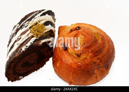 Roulé à la cannelle cuit roulé, roulé, sucré avec du miel et des raisins secs et rempli de crème anglaise et de chocolat, rouleau de gâteau suisse, combinaison de lumière Banque D'Images