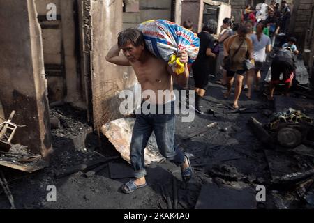 Un homme porte un sac de matériaux récupérés après un incendie dans une colonie informelle de colons de la ville de Quezon, à l'est de Manille, aux Philippines, mercredi, 28 décembre 2016. Selon les informations locales, une personne âgée est décédée car 1000 familles ont été déplacées par un incendie important mardi soir, à 27 décembre 2016. (Photo de Richard James Mendoza/NurPhoto) *** Veuillez utiliser le crédit du champ de crédit *** Banque D'Images