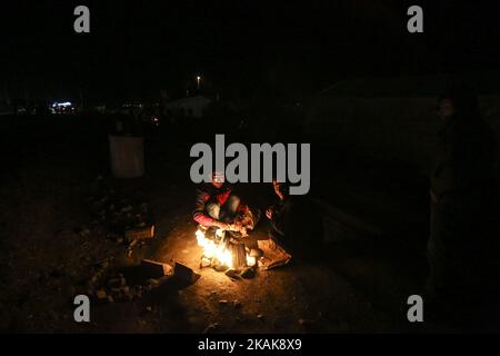 Les réfugiés et les migrants tentent de se réchauffer par des incendies dans le camp de fortune d'Idomeni, Grèce, février 2016. Ils utilisent tout pour soutenir le feu, même les plastiques, créant une atmosphère terrible et toxique. Les réfugiés sont bloqués à la frontière, car le passage de chemin de fer illégal est fermé. Depuis 2014, les réfugiés de Syrie, d'Irak, mais aussi d'Afghanistan, du Pakistan et d'autres pays du Moyen-Orient, ont commencé à affluer vers Idomeni afin de traverser les frontières grecques et d'entrer dans l'ARYM / République de Macédoine. Cette dernière et la Serbie au nord sont toutes deux en dehors de l'espace Schengen, c'est pourquoi le refus Banque D'Images