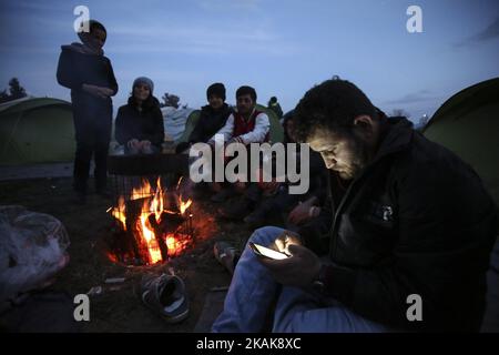 Les réfugiés et les migrants tentent de se réchauffer par des incendies dans le camp de fortune d'Idomeni, Grèce, février 2016. Ils utilisent tout pour soutenir le feu, même les plastiques, créant une atmosphère terrible et toxique. Les réfugiés sont bloqués à la frontière, car le passage de chemin de fer illégal est fermé. Depuis 2014, les réfugiés de Syrie, d'Irak, mais aussi d'Afghanistan, du Pakistan et d'autres pays du Moyen-Orient, ont commencé à affluer vers Idomeni afin de traverser les frontières grecques et d'entrer dans l'ARYM / République de Macédoine. Cette dernière et la Serbie au nord sont toutes deux en dehors de l'espace Schengen, c'est pourquoi le refus Banque D'Images