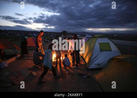 Les réfugiés et les migrants tentent de se réchauffer par des incendies dans le camp de fortune d'Idomeni, Grèce, février 2016. Ils utilisent tout pour soutenir le feu, même les plastiques, créant une atmosphère terrible et toxique. Les réfugiés sont bloqués à la frontière, car le passage de chemin de fer illégal est fermé. Depuis 2014, les réfugiés de Syrie, d'Irak, mais aussi d'Afghanistan, du Pakistan et d'autres pays du Moyen-Orient, ont commencé à affluer vers Idomeni afin de traverser les frontières grecques et d'entrer dans l'ARYM / République de Macédoine. Cette dernière et la Serbie au nord sont toutes deux en dehors de l'espace Schengen, c'est pourquoi le refus Banque D'Images