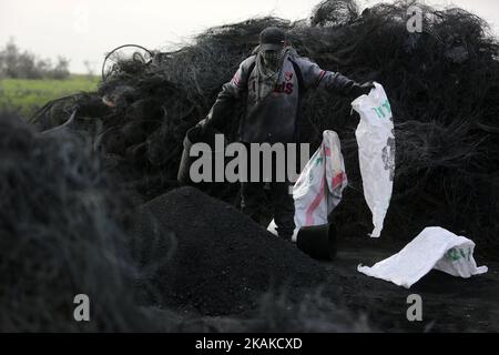 Un palestinien Ashraf Hillis travaille à la production d'un pigment noir destiné à être utilisé dans les matériaux de construction par la combustion de pneus de véhicules, dans la zone tampon à l'est de la ville de Gaza, le 25 janvier 2017. (Photo de Majdi Fathi/NurPhoto) *** Veuillez utiliser le crédit du champ de crédit *** Banque D'Images