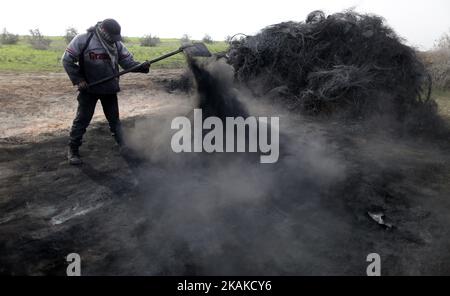 Un palestinien Ashraf Hillis travaille à la production d'un pigment noir destiné à être utilisé dans les matériaux de construction par la combustion de pneus de véhicules, dans la zone tampon à l'est de la ville de Gaza, le 25 janvier 2017. (Photo de Majdi Fathi/NurPhoto) *** Veuillez utiliser le crédit du champ de crédit *** Banque D'Images