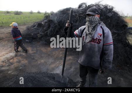 Un palestinien Ashraf Hillis travaille à la production d'un pigment noir destiné à être utilisé dans les matériaux de construction par la combustion de pneus de véhicules, dans la zone tampon à l'est de la ville de Gaza, le 25 janvier 2017. (Photo de Majdi Fathi/NurPhoto) *** Veuillez utiliser le crédit du champ de crédit *** Banque D'Images