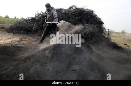 Un palestinien Ashraf Hillis travaille à la production d'un pigment noir destiné à être utilisé dans les matériaux de construction par la combustion de pneus de véhicules, dans la zone tampon à l'est de la ville de Gaza, le 25 janvier 2017. (Photo de Majdi Fathi/NurPhoto) *** Veuillez utiliser le crédit du champ de crédit *** Banque D'Images