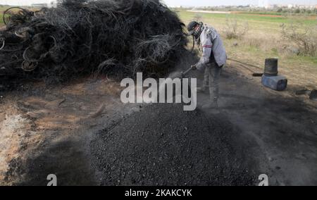 Un palestinien Ashraf Hillis travaille à la production d'un pigment noir destiné à être utilisé dans les matériaux de construction par la combustion de pneus de véhicules, dans la zone tampon à l'est de la ville de Gaza, le 25 janvier 2017. (Photo de Majdi Fathi/NurPhoto) *** Veuillez utiliser le crédit du champ de crédit *** Banque D'Images