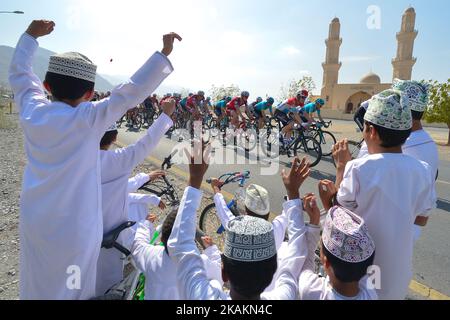 Un groupe de jeunes étudiants regardent un peloton de cavaliers passant par leur village, pendant la phase d'ouverture, a 176,5km de la plage d'Al Sawadi au parc de Naseem de la visite à vélo de 2017 d'Oman. Mardi, 14 février 2017, à Muscat, Oman. Photo par Artur Widak *** Veuillez utiliser le crédit du champ de crédit *** Banque D'Images