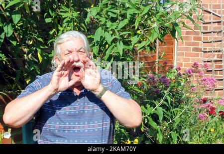 Un homme âgé ou âgé se fait les mains par-dessus la bouche et criant vers la caméra. Banque D'Images