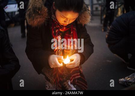 Une femme tient une bougie à la mémoire du défunt Shaoyo Liu. Plusieurs centaines de personnes venant principalement de la communauté chinoise française se sont rassemblées près du quartier de police du 19th arrondissement de Paris pour protester contre la mort de Shaoyo Liu dans sa maison il y a 2 jours, tué par la police française, sur 28 mars 2017. La famille de Shaoyo Liu accuse la police de tuer un innocent alors que la police dit qu'il a attaqué les policiers en premier. Paris (75), France, on 28 mars 2017. (Photo de Jan Schmidt-Whitley/NurPhoto) *** Veuillez utiliser le crédit du champ de crédit *** Banque D'Images