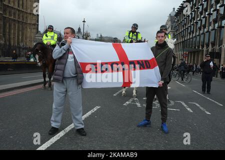 Deux hommes arborent un drapeau de la Croix de St George avec « l'Angleterre » écrit sur le pont de Westminster alors que les gens assistent à une veillée pour se souvenir des victimes de l'attaque terroriste de Westminster la semaine dernière sur 29 mars 2017 à Londres, en Angleterre. Les chefs religieux ont pris la direction d'une vigile comprenant des membres du public et des policiers sur le pont de Westminster exactement une semaine après que Khalid Masood a labouré une voiture de location dans des personnes traversant le pont de Westminster, tuant trois personnes. Masood a gagné l'entrée sur le terrain des chambres du Parlement poignardant le PC Keith Palmer à mort avant d'être tué par balle par la police armée. (Photo de Jay Shaw Baker Banque D'Images