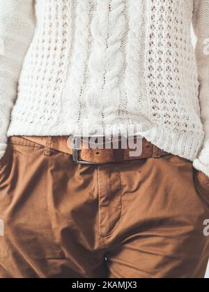 Femme en pull blanc à maille torsadée avec patter scandinave et pantalon chinos marron avec ceinture en cuir. Vêtements décontractés pour un temps de détente. Moderne urb Banque D'Images