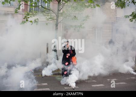 Une femme aînée couvre son visage comme gaz lacrymogène est projeté par la police émeute pendant la journée de travail mars à Paris sur 1 mai 2017 . Des milliers de Parisiens sont descendus dans la rue pour rejoindre une manifestation massive sur 1 mai. Différents collectifs et organisations ont appelé leurs militants à marcher contre les résultats des élections présidentielles de première tournée en France. Des affrontements ont eu lieu au cours de la marche entre des manifestes et des émeutes de la police. *** Veuillez utiliser le crédit du champ de crédit *** Banque D'Images