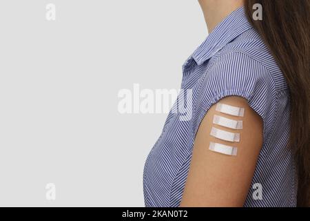 Quatre pansements médicaux sur le bras d'une jeune femme. Symbole de quatre doses de vaccin Covid-19, y compris les injections de rappel. Espace libre pour le texte. Banque D'Images