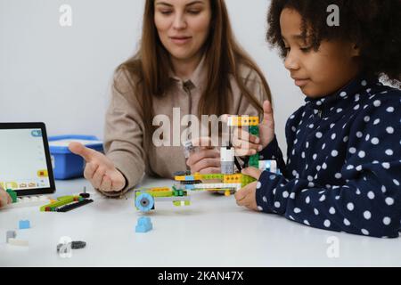 Des enfants multiethniques à la LEÇON STEM construire un robot dans une salle de classe avec une femme enseignante les enfants font un modèle de bras électronique à l'école de science moderne Banque D'Images