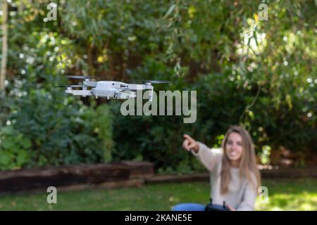 Accent sélectif sur le drone volant et la jeune femme floue pointant le quadriptère Banque D'Images