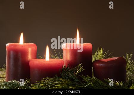 Couronne de l'Avent avec bougies rouges et trois bougies allumées avec des creux à feuilles persistantes avec espace pour les copies Banque D'Images