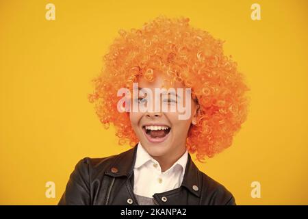 Visage amusant. Belle adolescente dans perruque isolée sur jaune. Perruque clown amusante. Banque D'Images