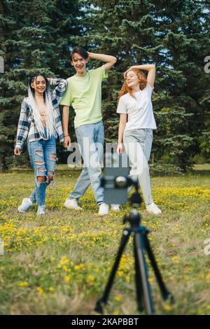 Portrait de trois adolescents de génération Z filmant des vidéos pour les médias sociaux dans le parc d'été. Enregistrement d'une vidéo pour un site de médias sociaux. Beau pour le style de vie Banque D'Images
