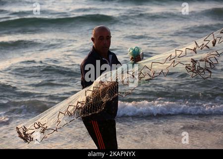 Le pêcheur palestinien Jihad al-Soltan (R) prépare son filet de pêche sur une plage dans le nord de la bande de Gaza 21 août 2017. Le pêcheur de Gaza dit qu'il a contacté Bethany et Zac à Greech qui a exprimé le plaisir de leur message reacha Gaza et ils passent leur régarda au peuple palestinien. Bethany et Zac ont été contactés par des joutnalistes pour trouver l'origine de ce message dans une bouteille histoire. Ils lui ont envoyé des photos d'eux par e-mail. Ils ont dit qu'ils étaient heureux de leur message à Gaza. (Photo de Majdi Fathi/NurPhoto) Banque D'Images