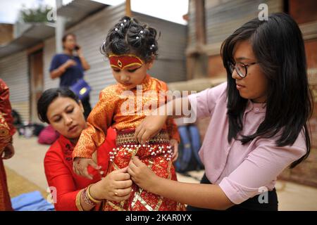 Un membre de la famille aide sa fille à porter une tenue traditionnelle lors de la célébration de la puja Kumari sur la place Basantapur Durbar, Katmandou, Népal, lundi, 04 septembre 2017. Au total, 108 jeunes filles de moins de neuf ans se sont rassemblées pour la puja Kumari, une tradition d'adoration, qui croit faire la puja sauver les petites filles des maladies et de la malchance à l'avenir. (Photo de Narayan Maharajan/NurPhoto) Banque D'Images