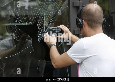 Un homme prend la photo de la fenêtre de magasin brisée alors que les militants d'extrême-droite exigent le propriétaire de magasin pour renouveler les peintures, Kiev, Ukraine, 3 septembre 2017 . Magasin de meubles de la rue Hrushevsky qui a enlevé le graffiti de Maidan (Révolution de la dignité) attaqué par les jeunes militants d'extrême-droite. (Photo par Sergii Kharchenko/NurPhoto) Banque D'Images