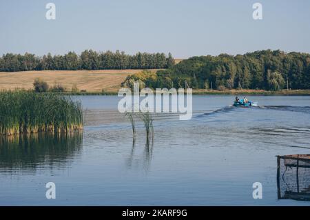 Deux hommes en bateau à moteur voilent à nouveau des vagues de dissection sur la rivière Banque D'Images