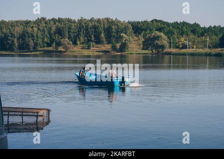 Deux fyshemen en bateau à moteur navigue sur la rivière contre la vue sur la forêt Banque D'Images