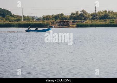 Deux fyshemen en bateau à moteur navigue sur la rivière, observateur sur la rive haute Banque D'Images