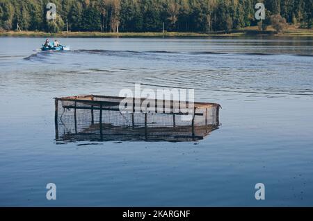 Filet de pêche dans l'eau, les hommes en bateau à moteur navigue sur la rivière Banque D'Images