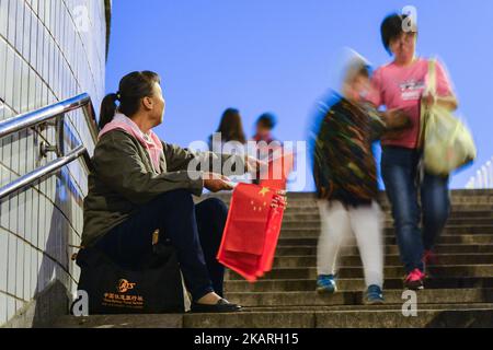 Vue sur une dame qui vend les drapeaux nationaux à l'entrée du métro près de la place Tiananmen à Pékin, en prévision de la prochaine Journée nationale pour célébrer le 68th anniversaire de la création de la République populaire de Chine. Le jeudi 28 septembre 2017, sur la place Tian'anmen, Pékin, Chine. Photo par Artur Widak Banque D'Images