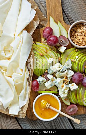 Ingrédients pour faire une tarte à la pâte phyllo, des fruits (raisins, poires), du fromage et des noix au miel. Cuisine méditerranéenne. Banque D'Images