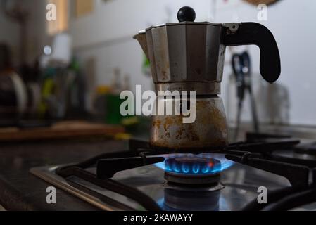 Dans ce gros plan un moka est vu sur le dessus d'un poêle de cuisine avec une flamme de gaz bleu. En raison de l'invasion de l'Ukraine par la Russie, les prix du gaz ont atteint un niveau record Banque D'Images