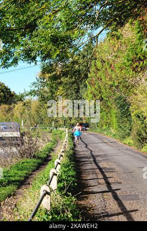 Vue arrière d'une jolie jeune femme blonde sur le chemin de halage qui s'étend sur la Tamise lors d'une journée d'automne à Shepperton Surrey, Angleterre, Royaume-Uni Banque D'Images