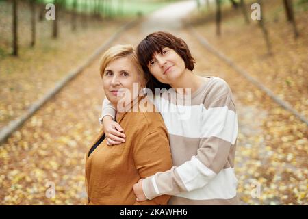 La mère caucasienne et sa fille séjournant dans un adorable parc d'automne. Portrait de la mère sénior et de la fille gaie adulte passant du temps ensemble à l'extérieur en saison de chute. Photo de haute qualité Banque D'Images