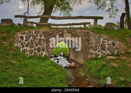 Un vieux pont avec des rampes en bois au-dessus d'une petite crique Banque D'Images