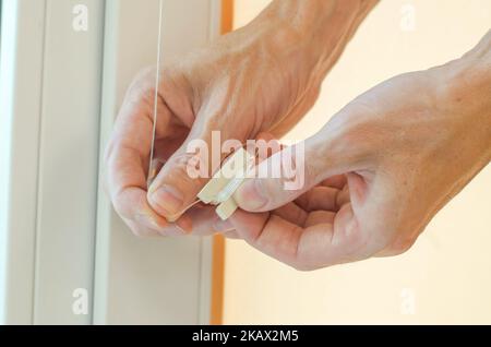 Gros plan des mains mâles en installant des stores à enroulement sur la fenêtre. Installation des stores roulants Banque D'Images