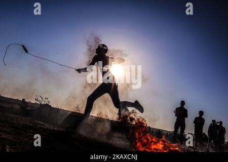 Un manifestant palestinien lance des pierres vers des soldats israéliens lors d'une manifestation près de la frontière de la bande de Gaza avec Israël, dans l'est de la ville de Gaza, samedi, 31 mars 2018 (photo de Mamen Faiz/NurPhoto) Banque D'Images